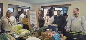 UAA volunteers standing behind a table of groceries for the UAA Community Food Larder