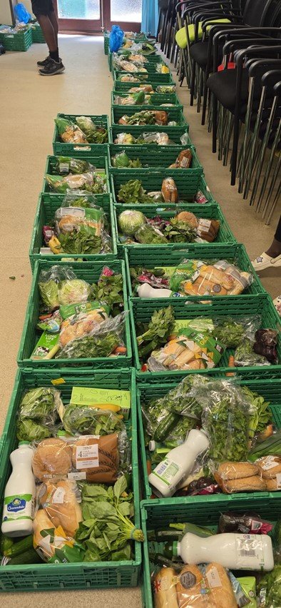Rows of green crates filled with vegetables and groceries prepared for the UAA Community Food Larder.
